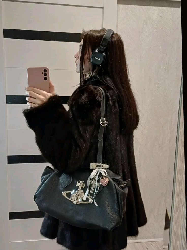 Woman in a black coat carrying a black Vivienne Westwood handbag